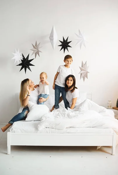 Gelukkige liefdevolle familie. moeder speelt met haar kinderen in het bed — Stockfoto