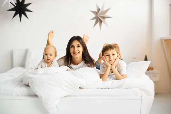 Glückliche liebende Familie. Mutter spielt mit ihren Kindern im Bett — Stockfoto