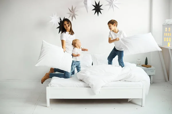 Ευτυχισμένη οικογένεια στην αγάπη. μητέρα παίζει με τα παιδιά της στο κρεβάτι — Φωτογραφία Αρχείου