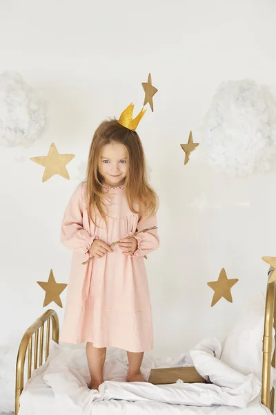 Malá princezna s kouzelnou hůlkou na posteli v oblacích — Stock fotografie