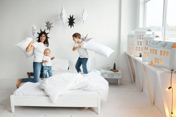 Gelukkige liefdevolle familie. moeder speelt met haar kinderen in het bed — Stockfoto