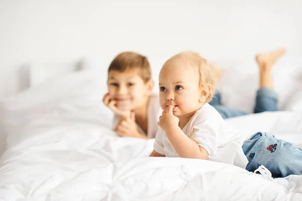 Bambini felici che giocano in camera da letto bianca. Ragazzino e ragazza, fratellino — Foto Stock