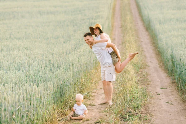 Молодая семья веселится со своим маленьким ребенком в поле — стоковое фото