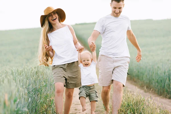 Eine junge Familie amüsiert sich mit ihrem kleinen Baby auf dem Feld — Stockfoto