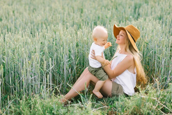 Une jeune mère et son petit enfant assis près du blé sur un — Photo