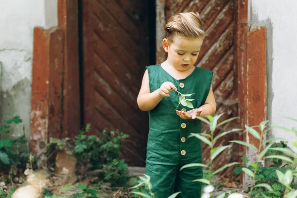 Um menino com cabelo branco em uma combinação verde joga ao lado do w — Fotografia de Stock