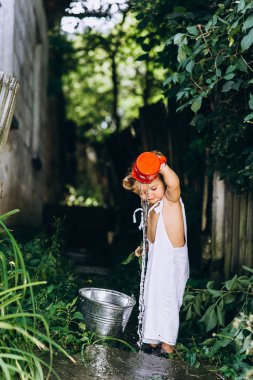 beyaz saç ve bir arada güzel bir çocuk bir kova su ve çitin yanında bir kupa ile oynanır