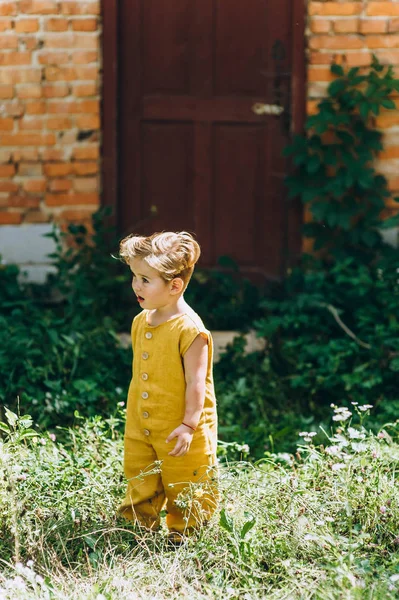 handsome little boy with white hair in a yellow combination against the background of the wall