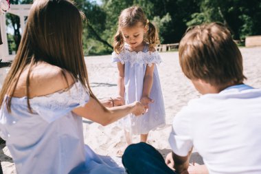 Mutlu bir aile açık havada birlikte vakit. Baba, anne ve kızı bir plajda piknik içinde
