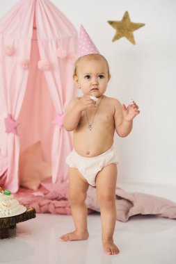 Büyük bir pasta yakınındaki bir sihirli değnek ile pembe bir çadırda küçük bir bebek. Doğum günü kutlama kavramı