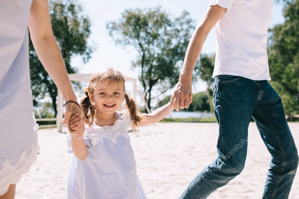 Happy family outdoors spending time together. Father, mother and daughter are having fun and running on a beach