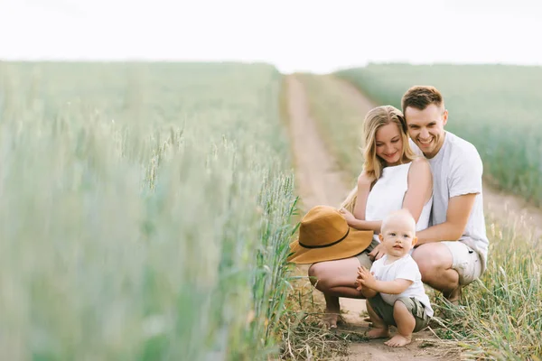 Una giovane famiglia si diverte con il loro bambino sul campo — Foto Stock