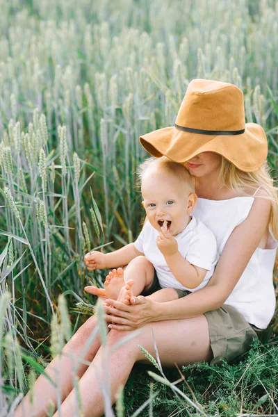 Une jeune mère et son petit enfant assis près du blé sur un — Photo