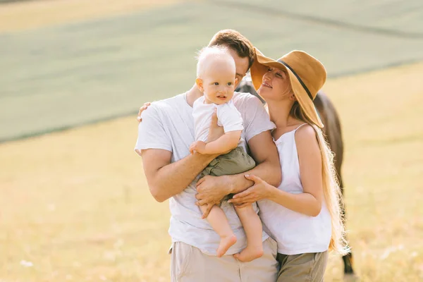 Eine junge glückliche Familie auf dem Feld hat Spaß — Stockfoto