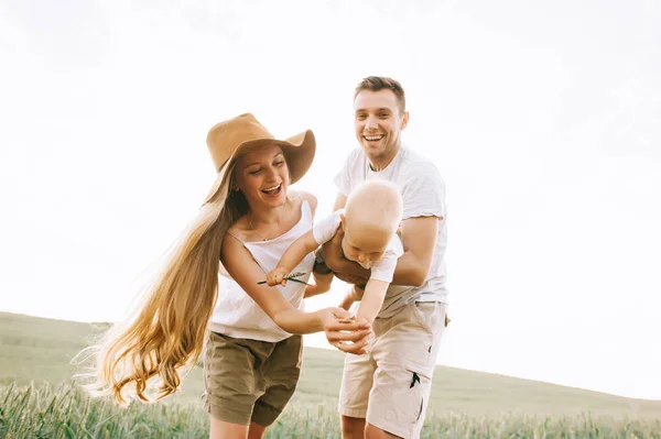 En ung glad familj i fältet har ett roligt — Stockfoto
