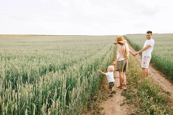 Молодая семья веселится со своим маленьким ребенком в поле — стоковое фото