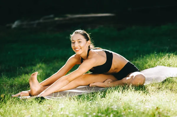 Hermosa chica de fitness haciendo ejercicio en la naturaleza en el soleado día de verano . —  Fotos de Stock