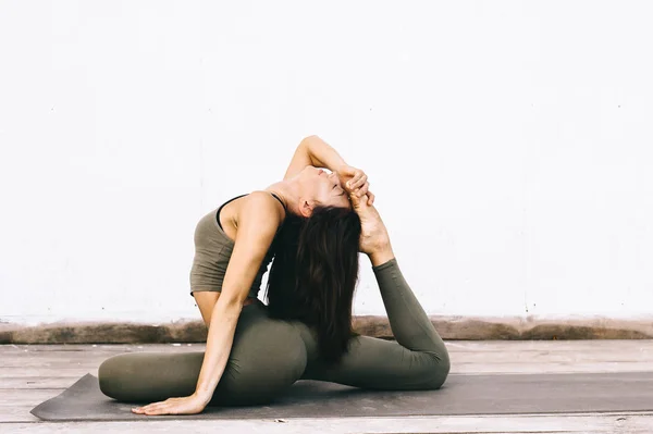 Attractive model in yoga pose on white background in sexual clot — Stock Photo, Image