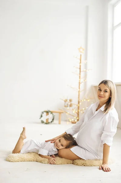 Mãe grávida feliz e sua filha se abraçam — Fotografia de Stock