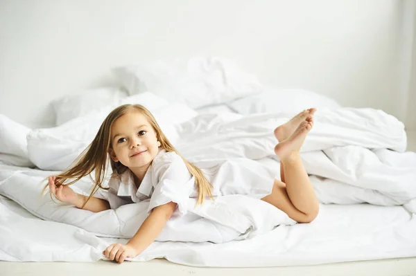 Un ritratto di una bella bambina nella camera da letto del mattino — Foto Stock