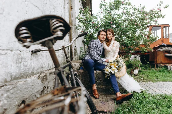 Um belo casal jovem noiva e noivo com uma bicicleta perto de idade — Fotografia de Stock