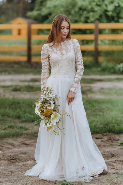 Seorang pengantin muda yang cantik dengan karangan bunga aster di lapangan — Stok Foto