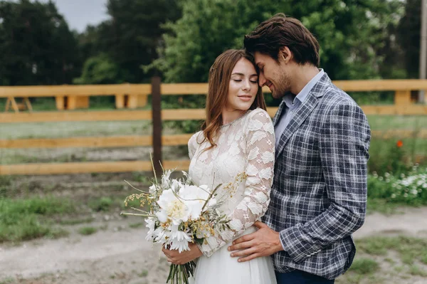 Beautiful young couple bride and groom walking near the wooden f — Stock Photo, Image