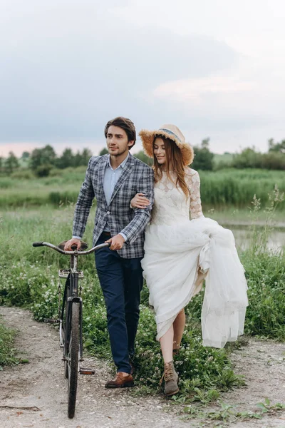 Hermosa pareja joven novia y novio caminando en un campo con un —  Fotos de Stock