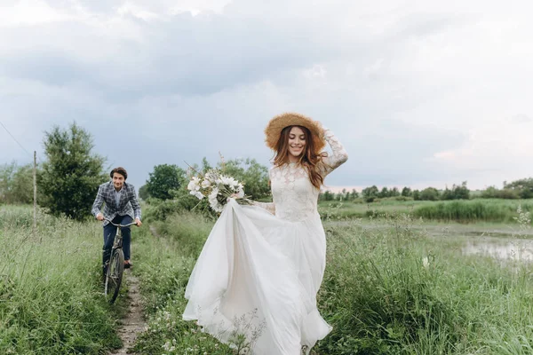 Krásný mladý pár nevěsta a ženich procházky v poli s — Stock fotografie