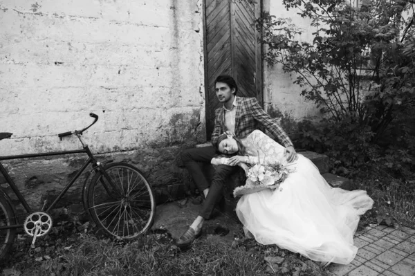 A beautiful young couple bride and groom with a bicycle near old — Stock Photo, Image