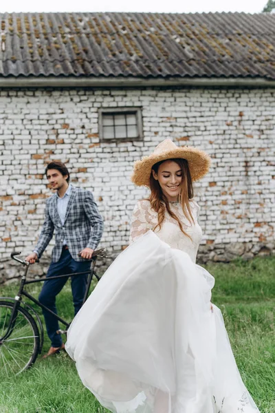Um belo casal jovem noiva e noivo com uma bicicleta perto de idade — Fotografia de Stock