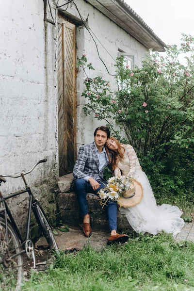Um belo casal jovem noiva e noivo com uma bicicleta perto de idade — Fotografia de Stock