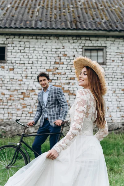 Um belo casal jovem noiva e noivo com uma bicicleta perto de idade — Fotografia de Stock