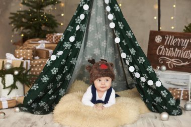 Çadırda ve Noel 'de şapkası halıda olan şirin bir bebek.