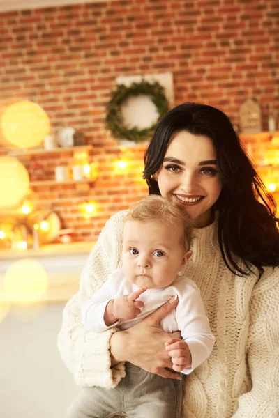 Eine schöne junge Mutter mit einem Baby in einem weihnachtlich dekorierten ro — Stockfoto