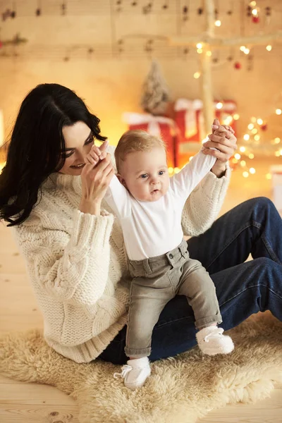 Una hermosa madre joven con un bebé en una Navidad decorada ro — Foto de Stock