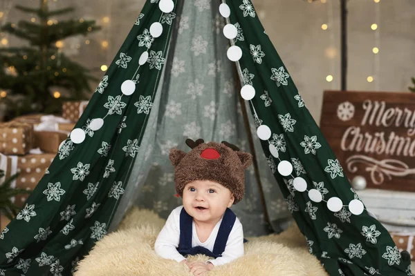 Lindo bebé con un sombrero en la alfombra en una tienda de campaña y tr Navidad — Foto de Stock