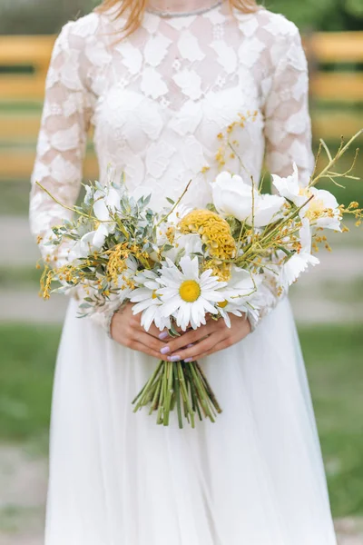 Krásná mladá nevěsta s kyticí sedmikrásek na poli — Stock fotografie