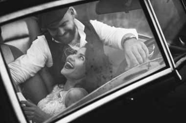 Şık bir düğün çifti, gelin, damat retro arabada sarılıyor. Rüzgarlar