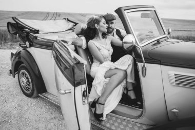 Şık bir düğün çifti, gelin ve damat retro arabada sarılıyorlar.. 