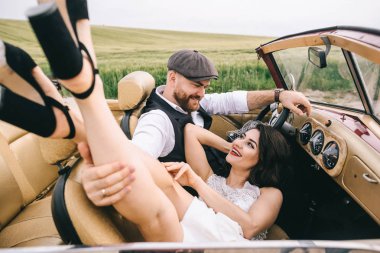 Şık bir düğün çifti, gelin ve damat retro arabada sarılıyorlar.. 