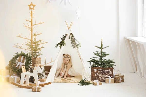 Een portret van een klein meisje in de buurt van de wigwam en kerstboom u — Stockfoto