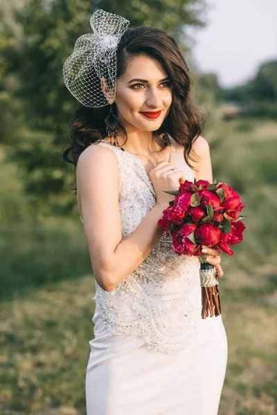 Novia con estilo con un ramo en un campo cerca del lago. Tetona retro —  Fotos de Stock