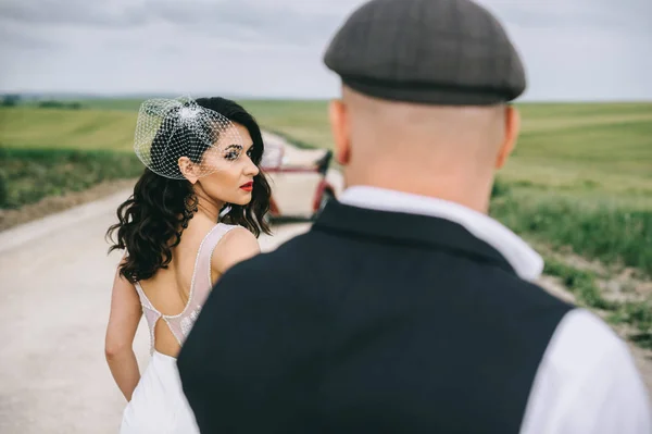 Casal elegante, noiva, noivo andando em uma estrada de campo nea — Fotografia de Stock