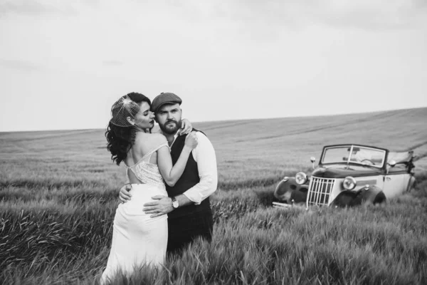 Elegante pareja de boda, novia, novio en un campo verde cerca de retr —  Fotos de Stock