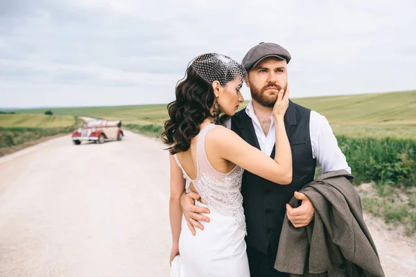 Стильна весільна пара, наречена, наречений на польовій дорозі біля ретро — стокове фото