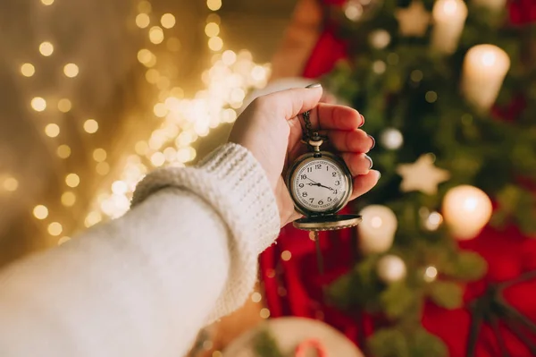 Mano femenina sostiene reloj sobre fondo borroso luces — Foto de Stock