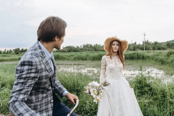 Krásný mladý pár nevěsta a ženich procházky v poli s — Stock fotografie