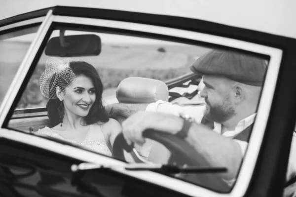 Elegante pareja de boda, novia, novio abrazándose en coche retro. Vientos —  Fotos de Stock