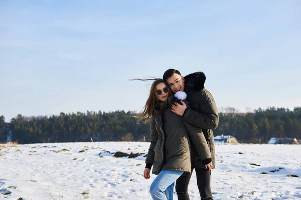 Счастливая пара обнимается и смеется на улице зимой — стоковое фото